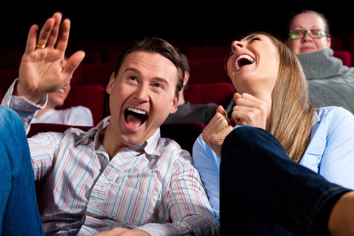 Two people laughing and having fun at a movie theater.