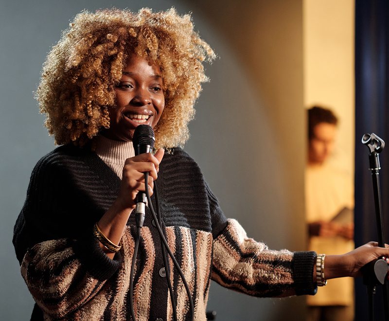 A woman with curly hair is holding a microphone.