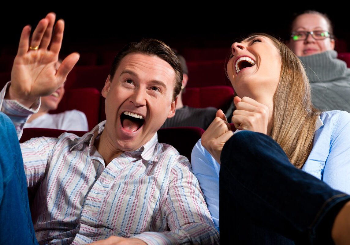 Two people laughing and having fun at a movie theater.