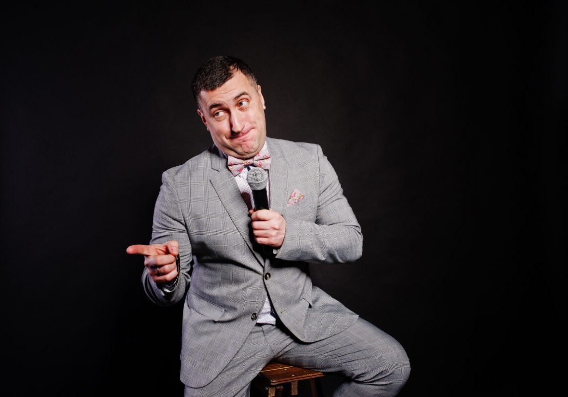 A man in a suit and tie holding a microphone.